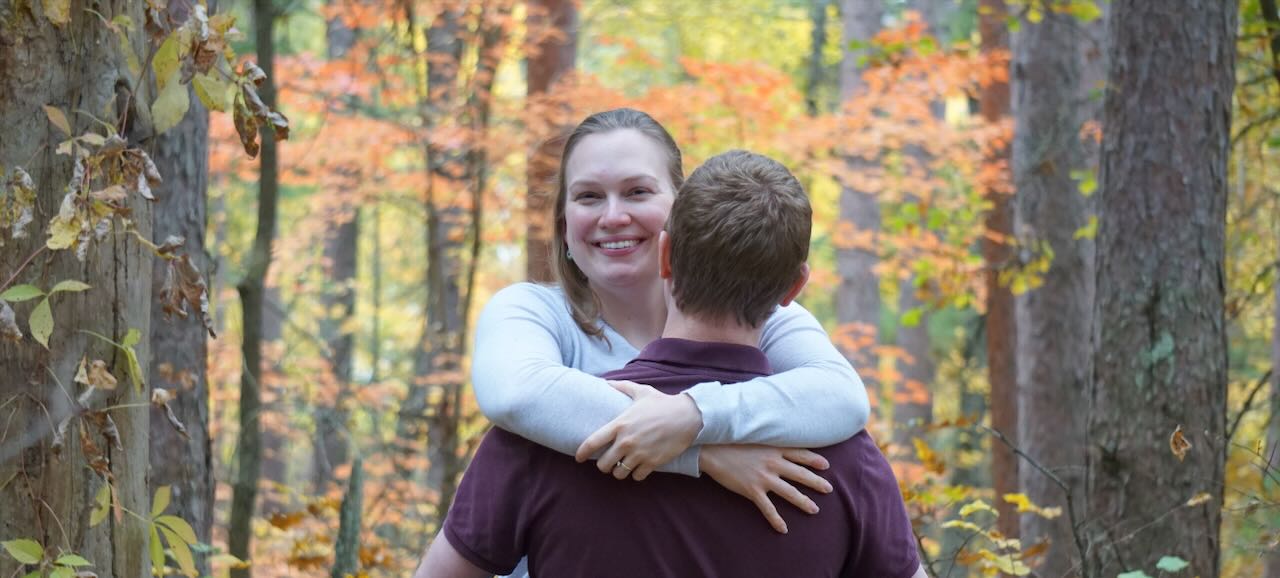 Josh has his back facing the camera while Whitney is straddeling his hips and smiling gracefully at the camera.