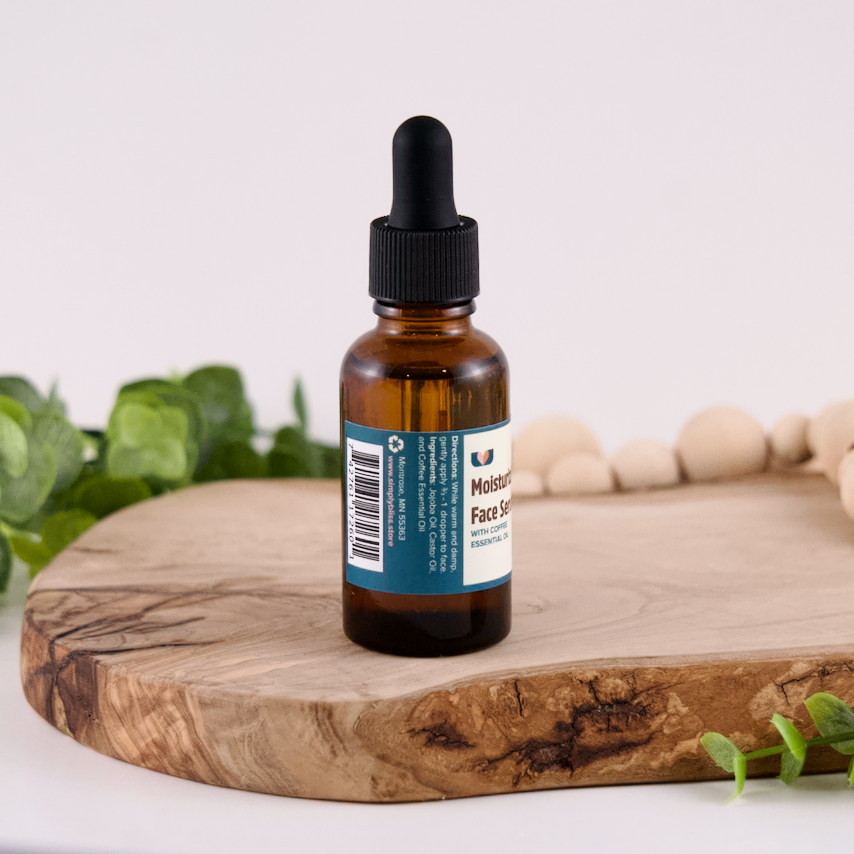 Bottle of facial serum on a wooden board with greenery